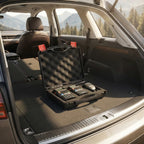 Black briefcase with electronic devices on a car trunk with mountains in the background